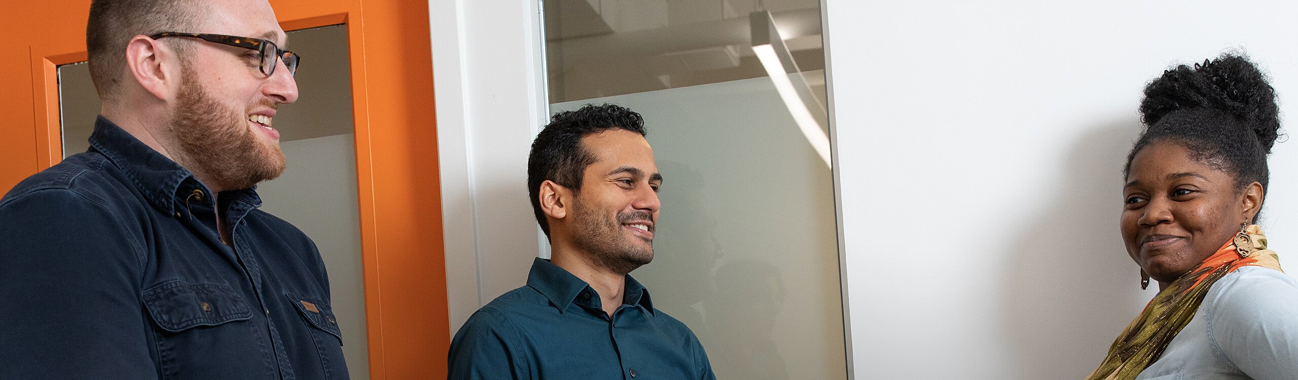 Search Analysts Sivan Philo and Saad Qureshi stop for a friendly chat in the office hallway with Search Associate Imani Doyle