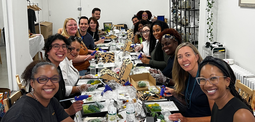 A large group of colleagues smiling together during a team crafting activity.