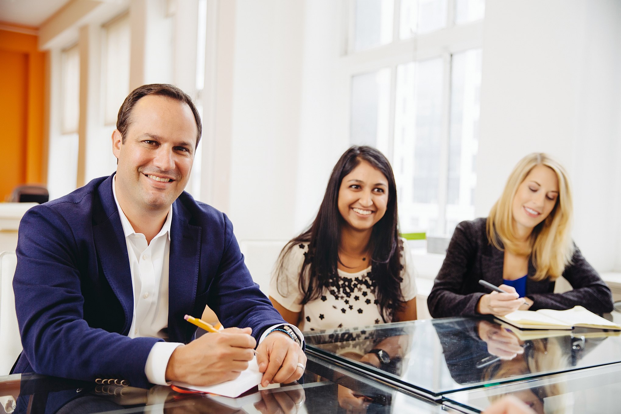 A diverse group of co-workers sit happily together during an office meeting