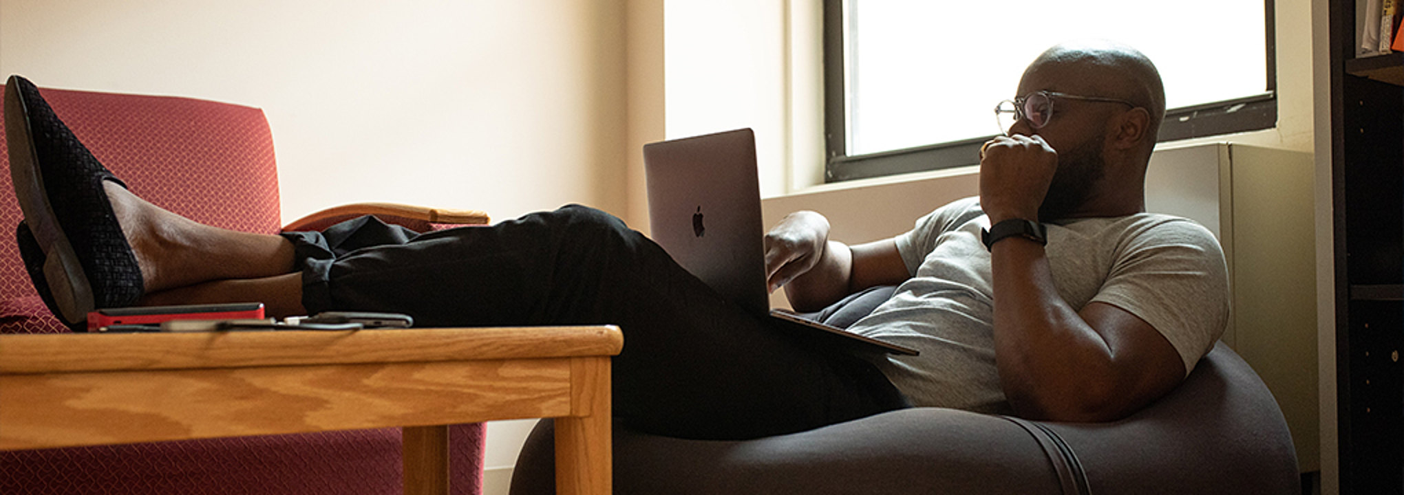 Man working on laptop while sitting in bean bag chair