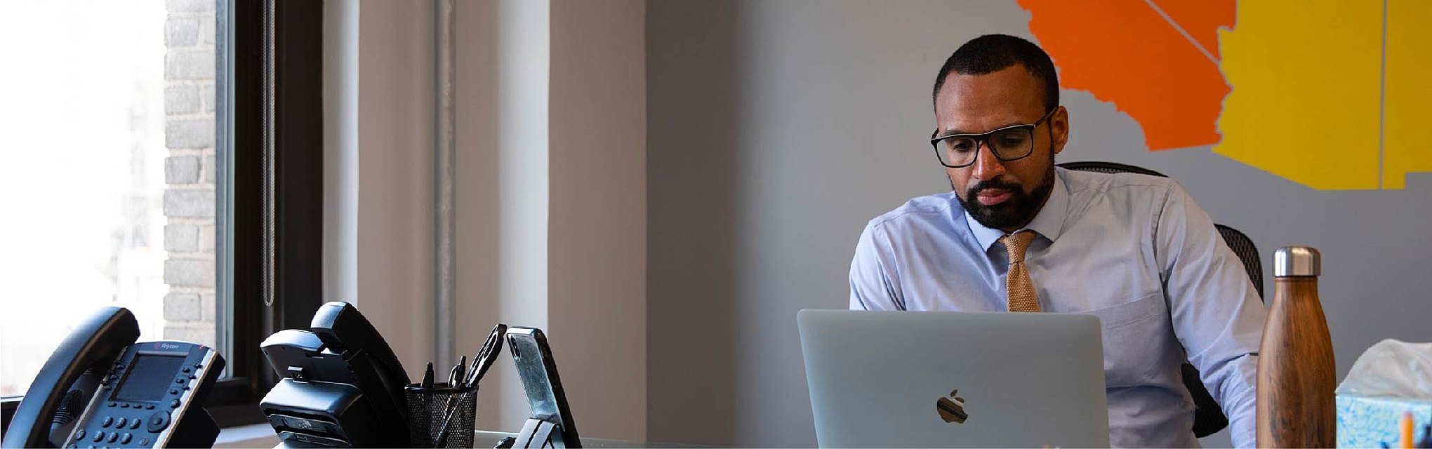 Search consultant Omar Lopez sits at his desk, looking at his laptop.