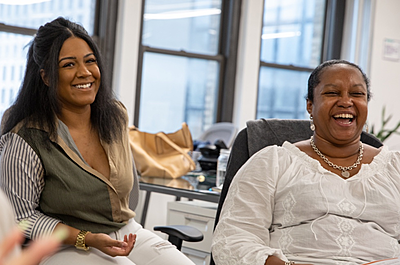 Two people sit in the On-Ramps office, laughing and smiling. 